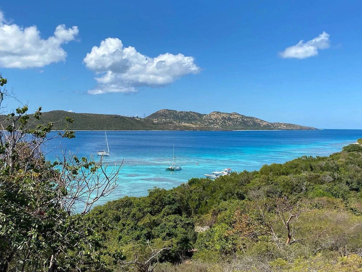 View over the reef shallows from Culebrita toward Culebra with boats at anchor
