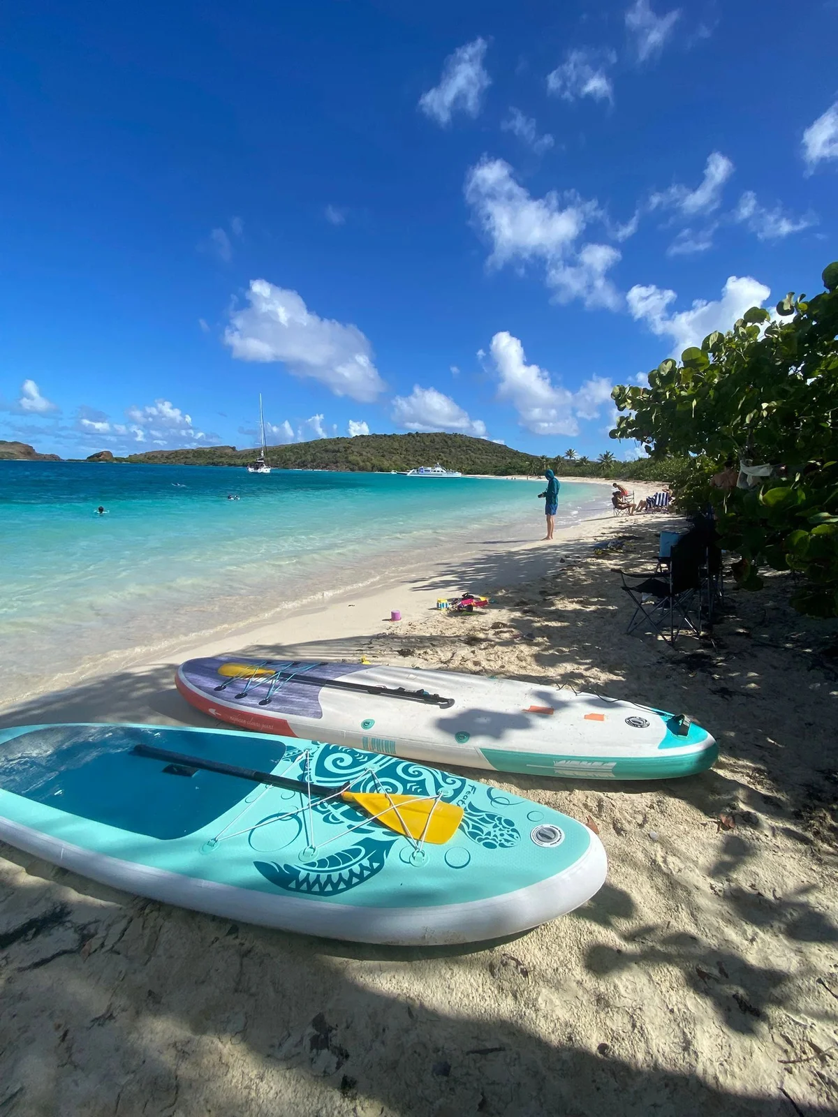 Paddleboards on the sand at a Culebrita beach with sailboats offshore