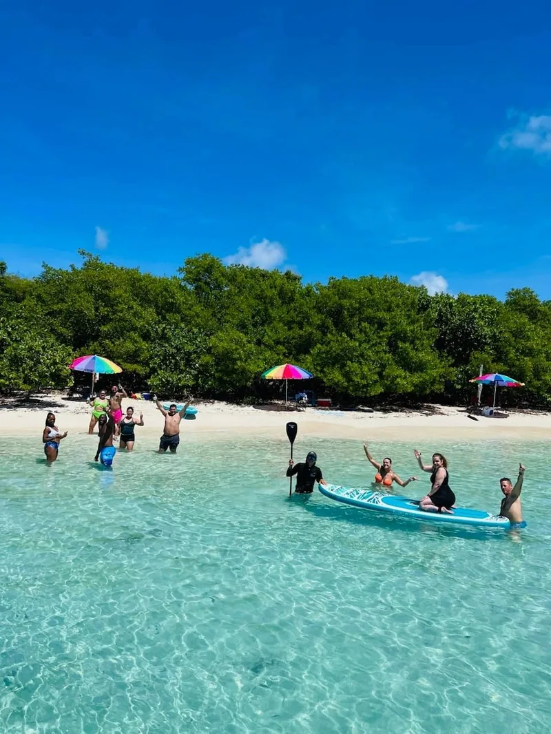 Guests swimming in clear water off a Culebrita beach with umbrellas on the sand