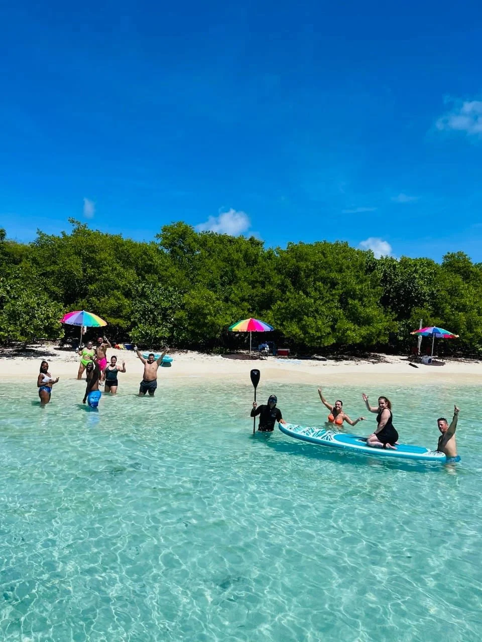 Guests swimming in clear water off a Culebrita beach with umbrellas on the sand