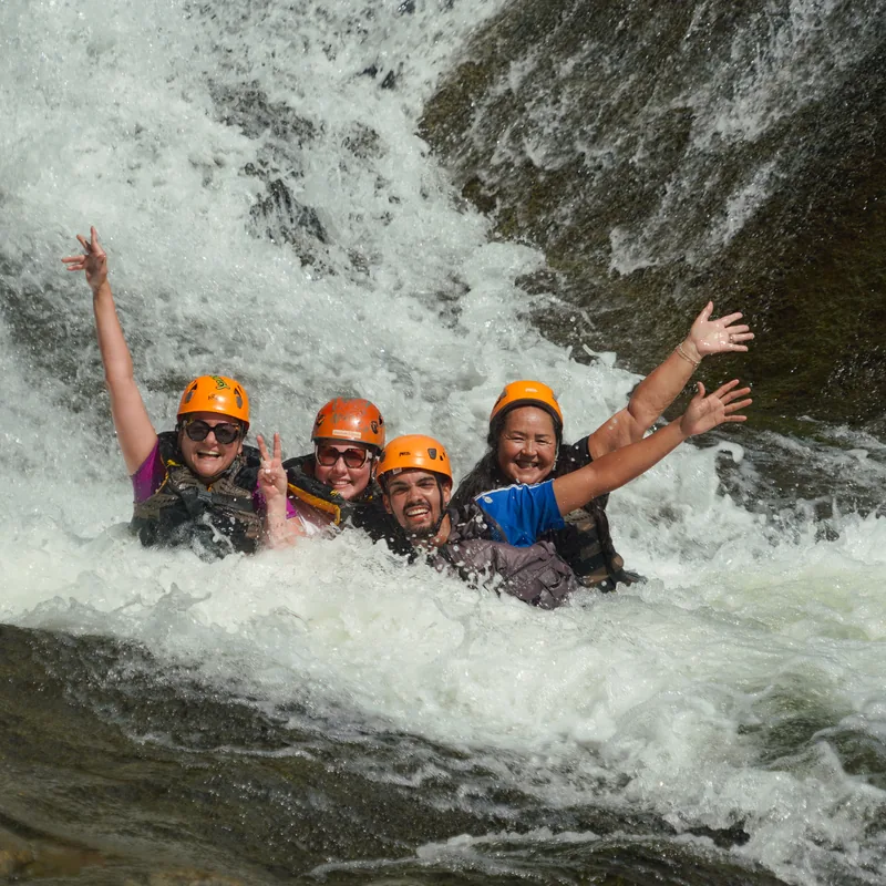 Small group body rafting through river rapids in helmets and life jackets, El Yunque, Puerto Rico