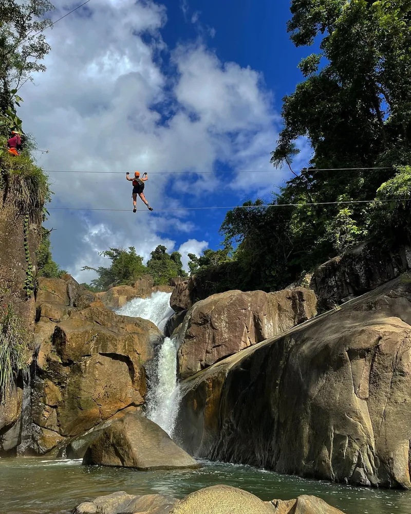 Guest crossing a line strung above a waterfall canyon, El Yunque, Puerto Rico