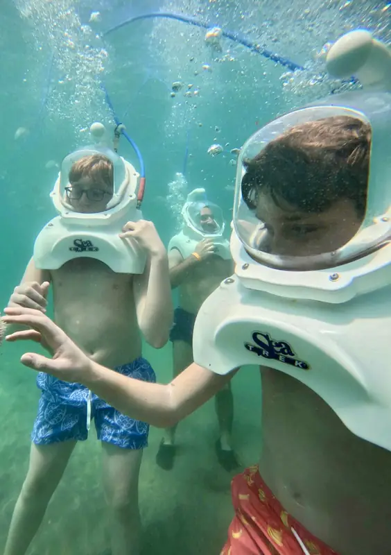 Kids in dive helmets walking underwater together on a San Juan helmet dive, Puerto Rico