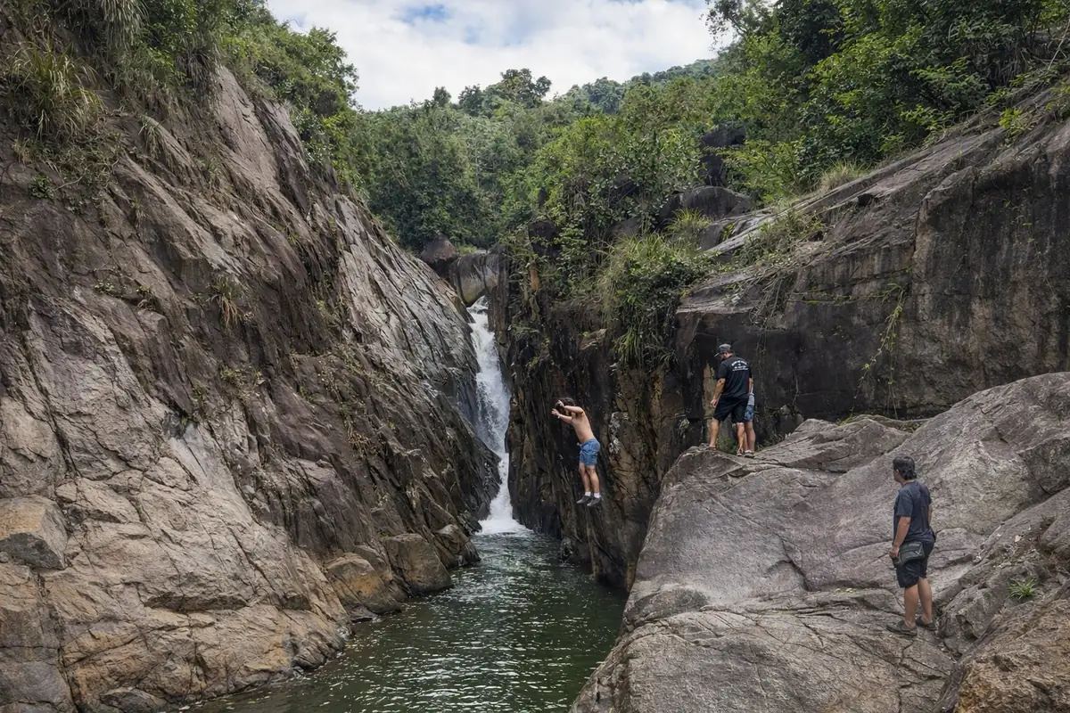 Guest cliff jumping into gorge pool at Charco El Hippie on Discover Naguabo tour