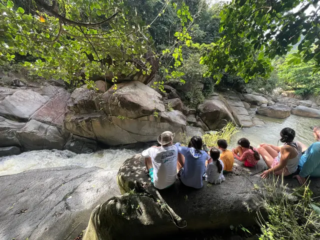 Family group sitting on rocks beside the flowing river at Charco El Hippie Naguabo
