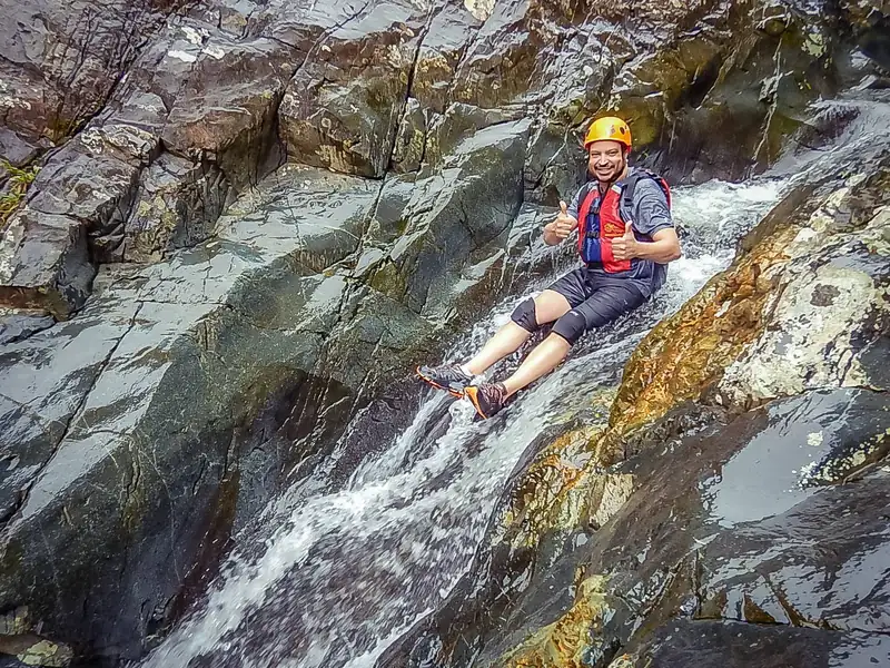Guest sliding down a natural rock waterslide in El Yunque