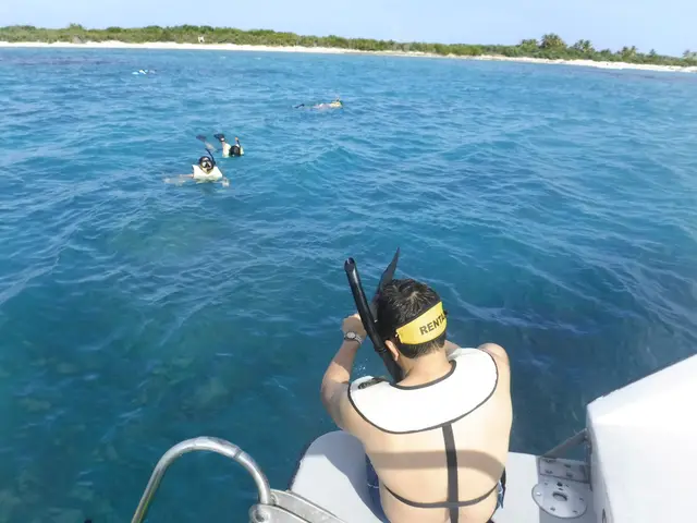 Guest about to enter turquoise water with white sand island in the distance