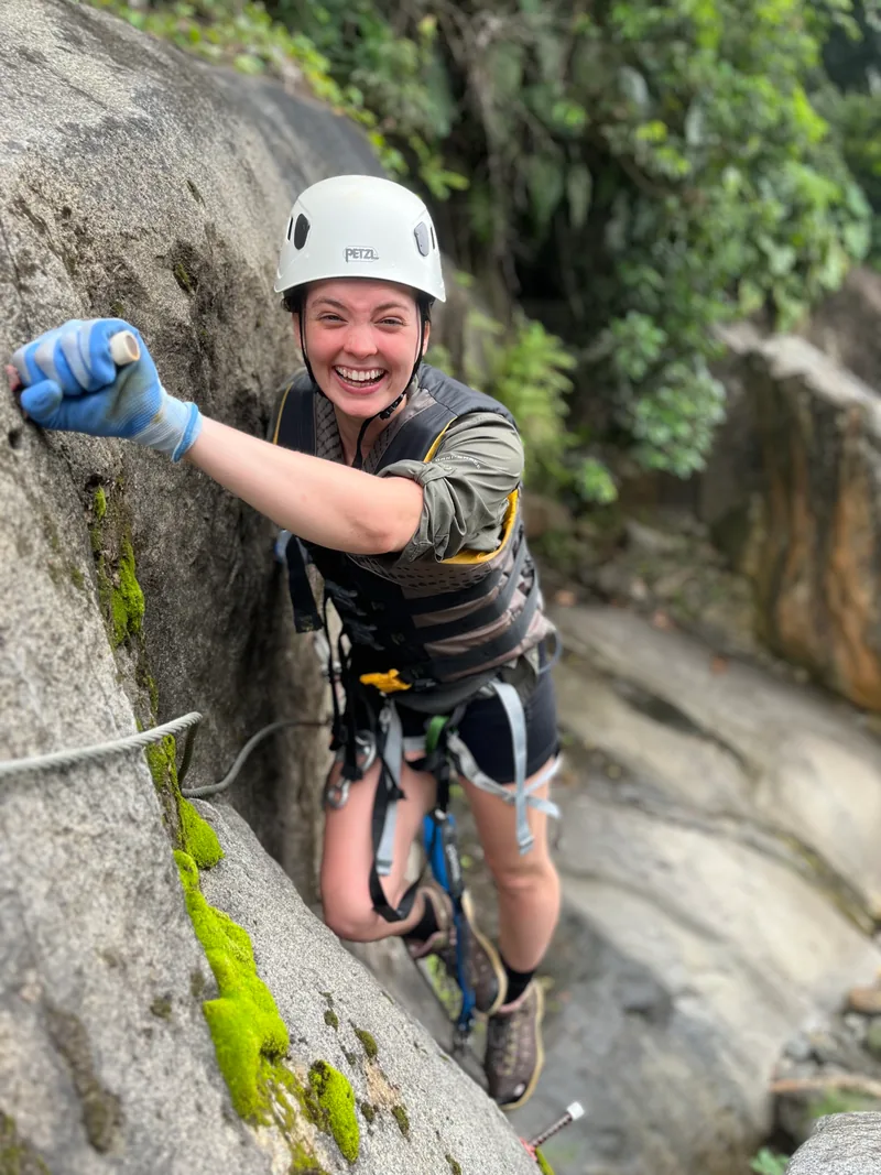 Climber clipped into steel cable and rungs on a rock face, via ferrata, El Yunque, Puerto Rico