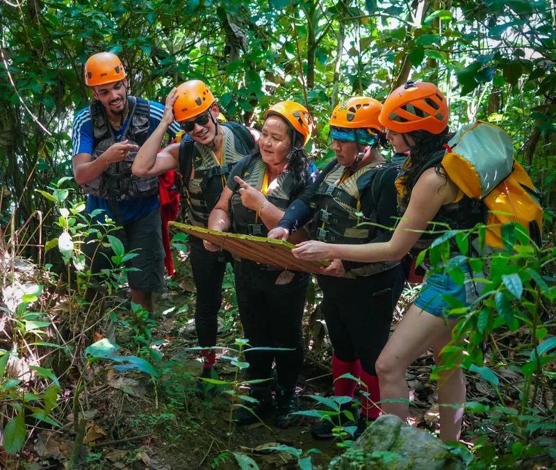 Small guided group in helmets on a forest footpath to the river, El Yunque, Puerto Rico