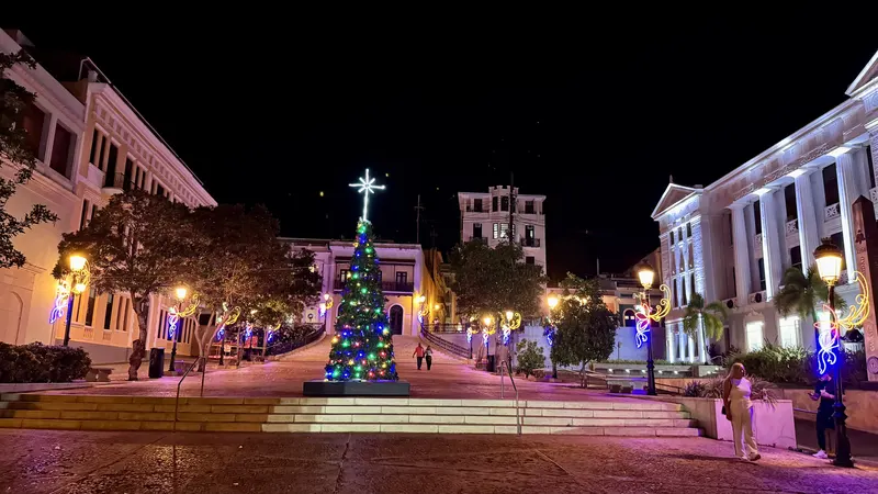 Christmas tree and holiday lights on a festive town plaza at night, the kind of plaza you explore in Caguas